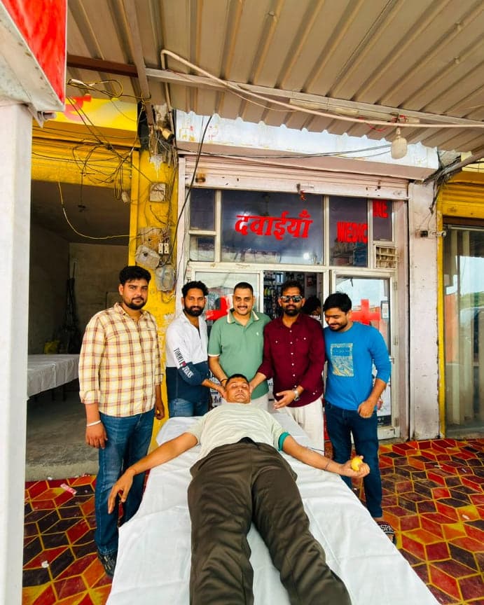 Blood donor lying on a camp bed set up directly outside the Allomart Pharmacy medical store in Jaipur